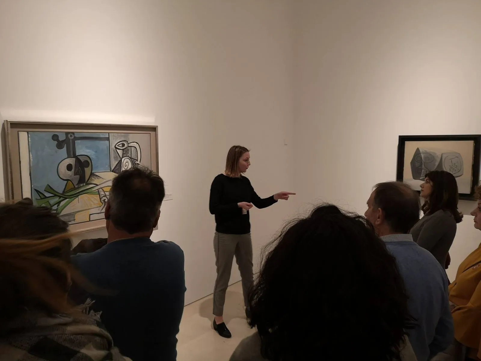 Anaïs points towards a blue and yellow canvas and the group turns to follow her hand.